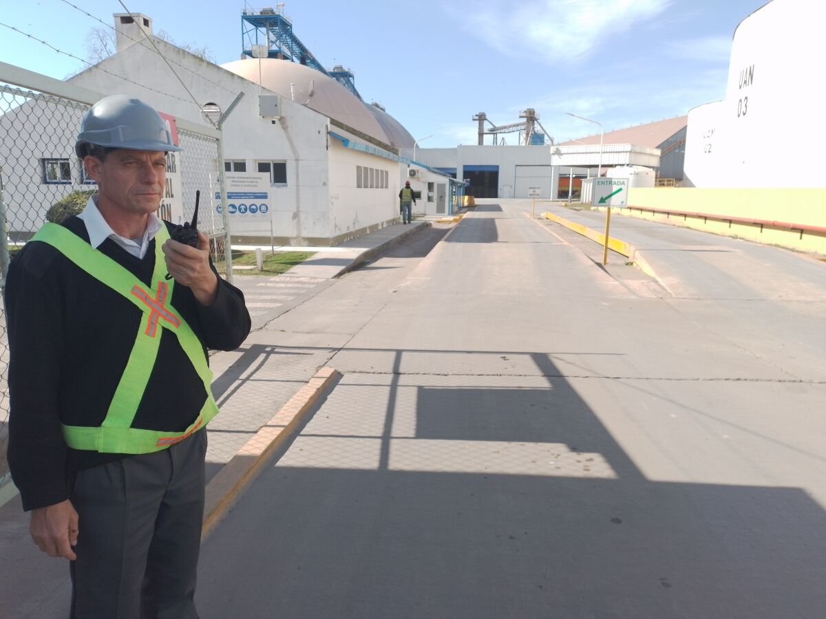 Guardia de seguridad parado en la entrada de un predio con un intercomunicador en la mano